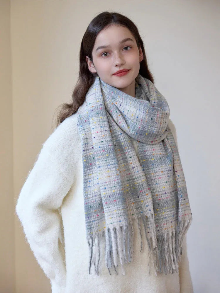 A young woman smiles and poses in a white sweater and a plaid scarf.