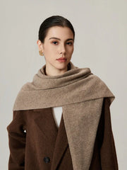 Woman wearing a beige scarf draped over a brown coat, front view