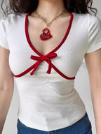 Detail of the neckline and bow on a white top with red trim.