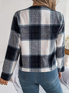 Back view of a woman wearing a cropped buffalo plaid jacket and blue jeans.