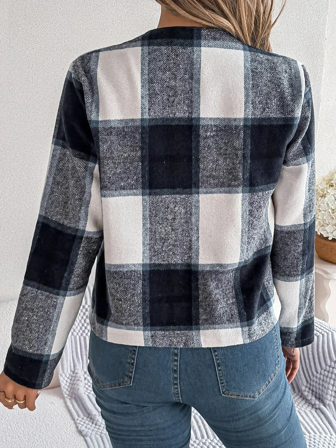 Back view of a woman wearing a cropped buffalo plaid jacket and blue jeans.