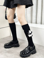 Fashionable outfit featuring knee-high black socks with panda charms and chunky platform sandals