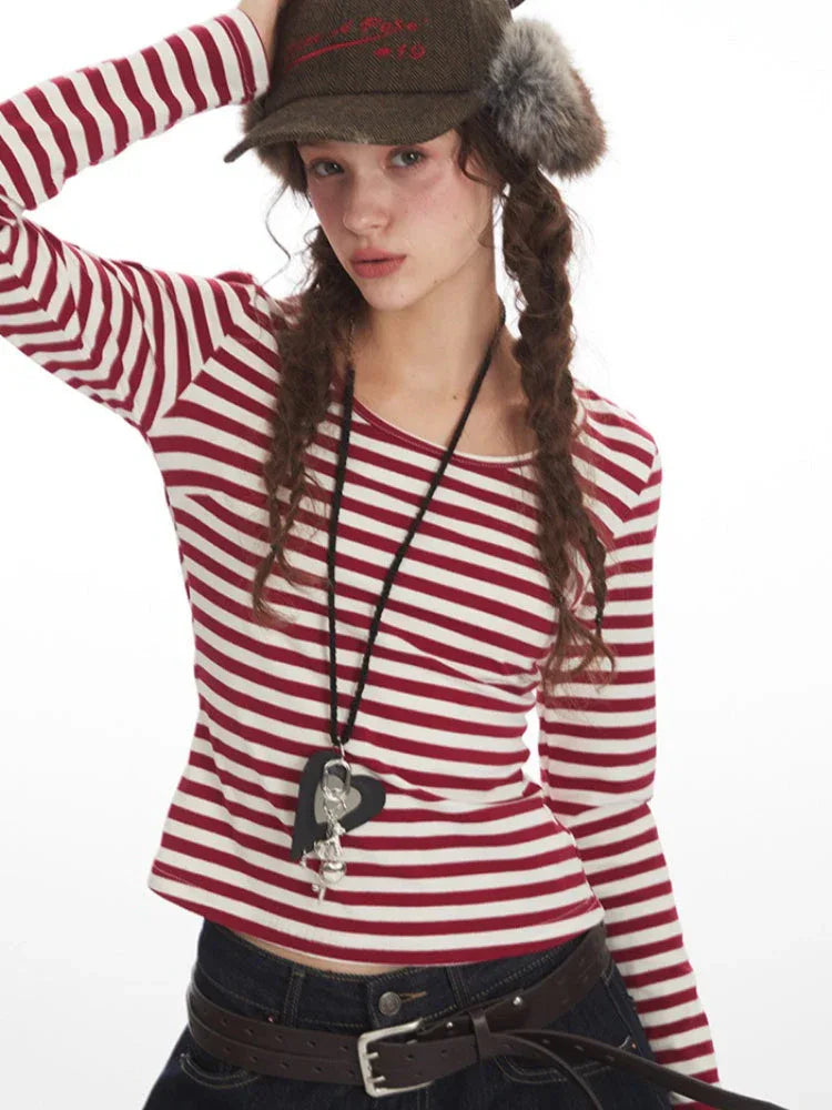 Close-up of a woman's face and upper body wearing a red and white striped long-sleeved shirt and a fur-trimmed hat.