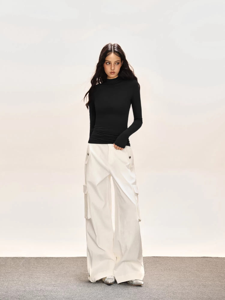 Full body shot of a woman in a black long-sleeve turtleneck top and white cargo pants.