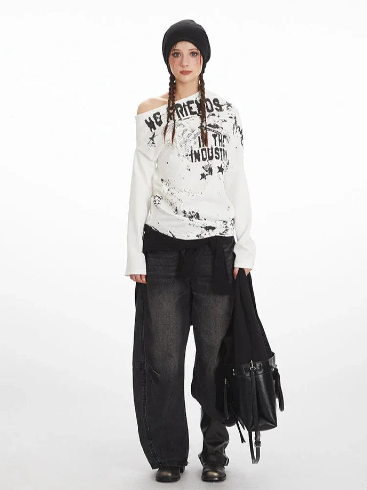 Model wearing a white long-sleeved off-the-shoulder top with distressed graphic print and black wide-leg jeans.