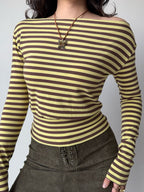 Front view of a woman wearing a yellow and brown striped off-the-shoulder long-sleeve top.