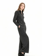 Model wearing a charcoal grey knit zip-up jacket and matching wide-leg pants, side view with hands in pockets.