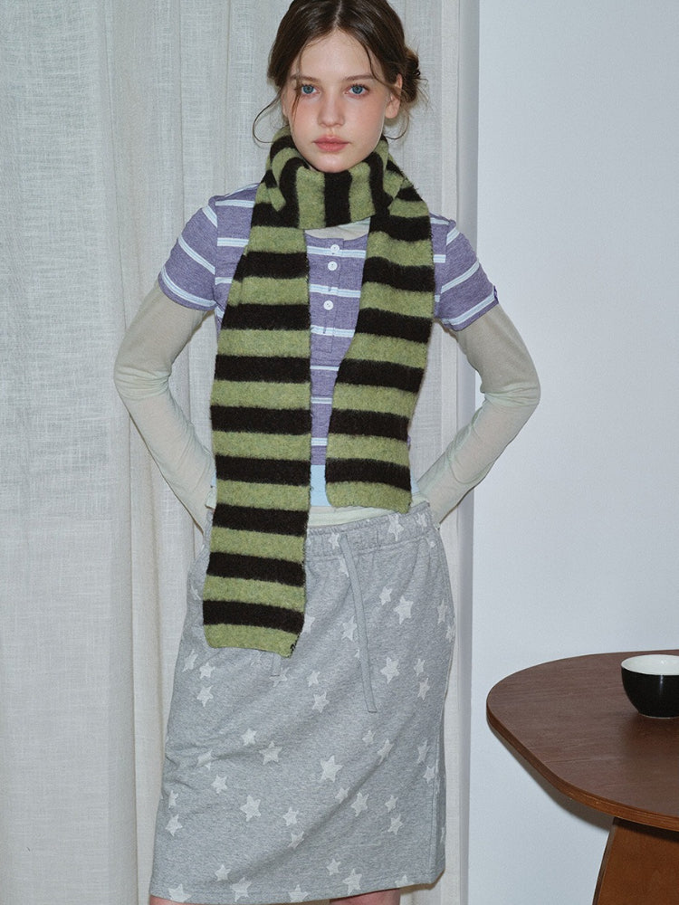 Woman wearing a striped scarf over a purple striped shirt and grey sweatpants with stars.