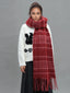 Front view of a woman modeling a white graphic sweater and a voluminous red plaid scarf.