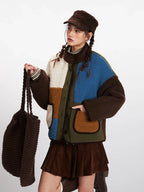 Close-up front view of a woman wearing a colorblock fleece jacket, holding a brown tote bag