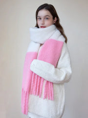 Close-up of a woman wearing a white sweater and a white and pink two-tone fuzzy knit scarf with fringe trim.