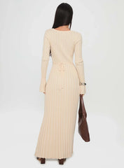 Back view of a woman in a cream ribbed knit maxi dress, highlighting the tie waist detail and maxi length.