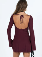 Back view of a burgundy long sleeve mini dress with an open back and tie closure