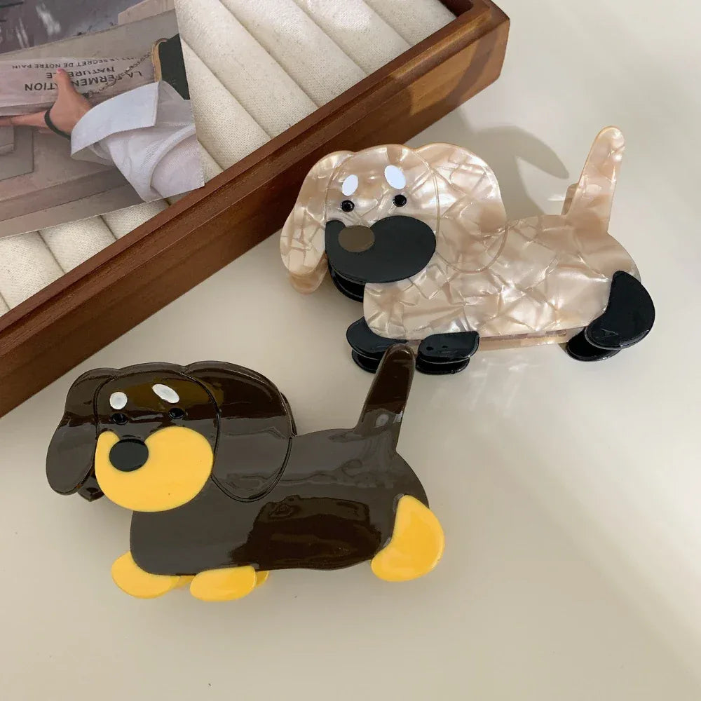 Two dachshund hair claw clips, one brown and yellow, the other beige and black, on a table