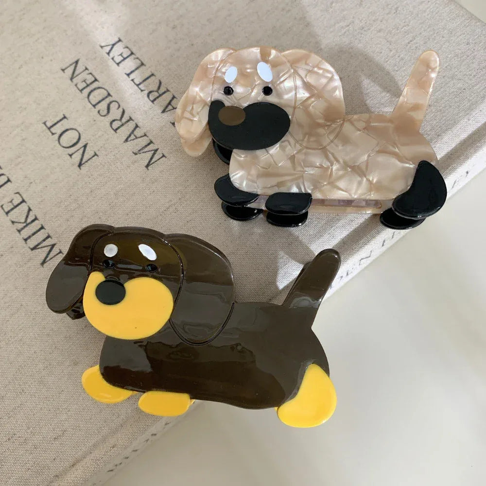Two dachshund hair claw clips, one brown and yellow, the other beige and black, on books