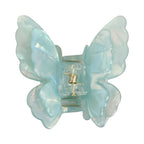 Close-up of a light blue iridescent butterfly claw clip with a gold spring