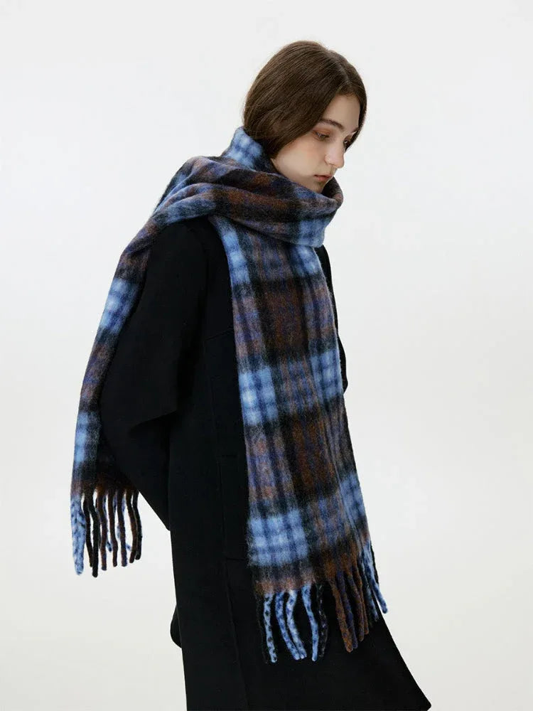 Side view of a woman wearing a black coat and a blue and brown plaid scarf.