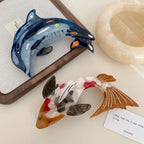 Koi fish hair clip and blue dolphin hair clip on a wooden frame