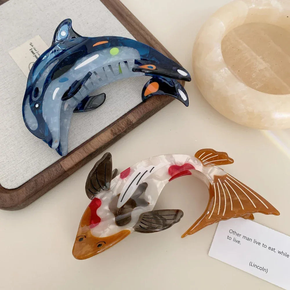 Koi fish hair clip and blue dolphin hair clip on a wooden frame