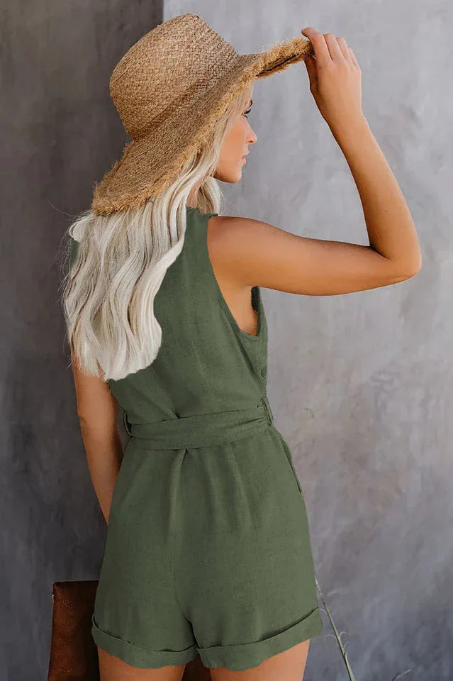 Back view of a woman wearing a sleeveless olive green romper with a V-neck, button-up front, and self-tie waist. Secondary image