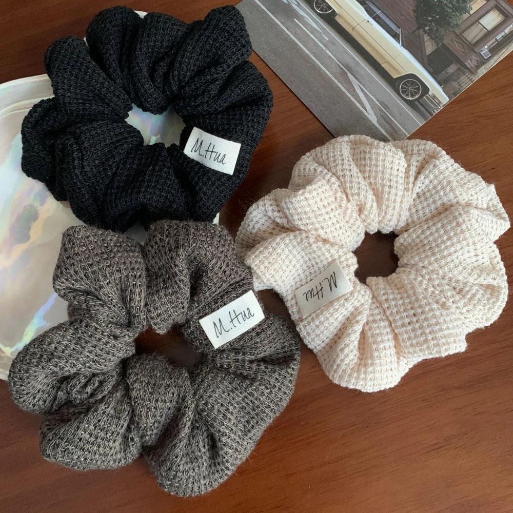 Close-up of black, grey, and beige waffle knit scrunchies