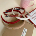 Close-up of padded headbands in red, beige, white, and plaid with a pink mug and book