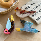A close-up view of three acrylic resin bird brooches, showcasing their detailed designs and bright colors.