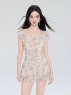Model wearing a light-colored short dress with a butterfly print and ruffled details.