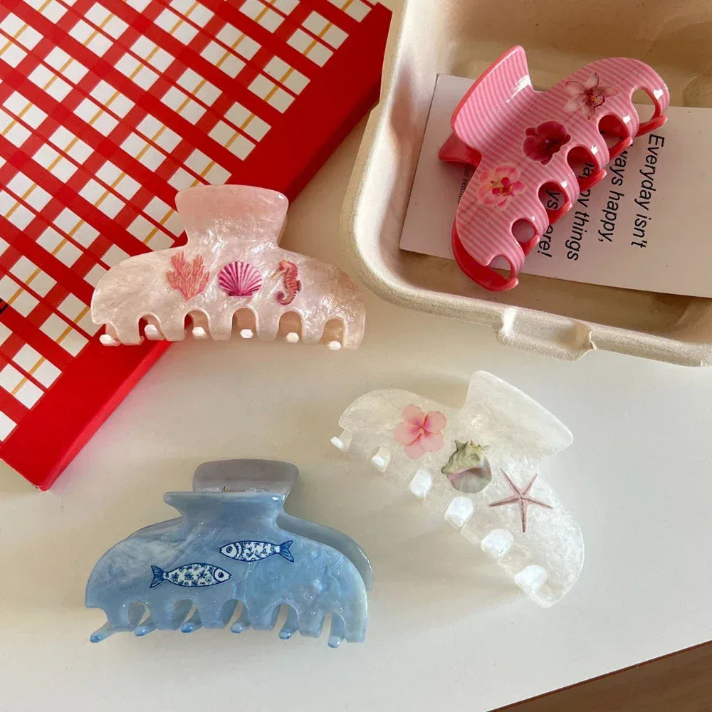 Four colorful hair claw clips arranged on a table, featuring various designs