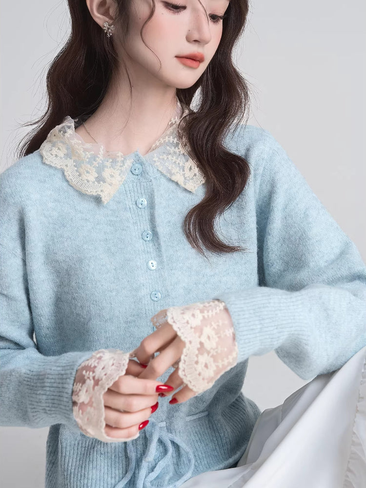 Close-up of a woman's chest and hands wearing a light blue knit cardigan with a white lace collar and cuffs.