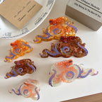 An assortment of octopus-shaped hair clips, showcasing translucent materials in orange, brown, and pinkish-white tones with distinctive white polka dots and blue tentacle patterns.