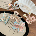 Assortment of pastel hair clips featuring bows, butterflies, and floral designs arranged on a wooden surface