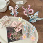 Various hair clips with bow and butterfly designs, some with stripes and floral accents, displayed on a white tray