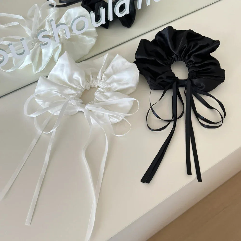 black and white satin scrunchies with long ribbon ties displayed on a white surface
