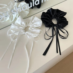black and white satin scrunchies with long ribbon ties displayed on a white surface