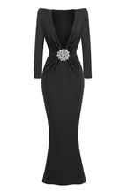 Black floor-length dress with a deep V-neck, long sleeves, and a jeweled embellishment at the waist.