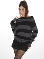 Model wearing a grey and black striped sweater styled off-the-shoulder, black shorts, black tights with stars, and black boots, touching her shoulder.