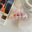 Light pink marbled claw clip with seashell, seahorse, and coral embellishments