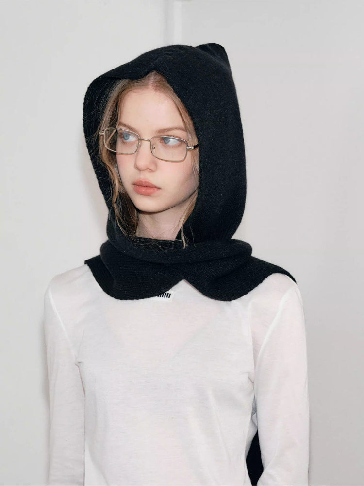 Close-up of a woman wearing a black hooded scarf with a large bow detail.