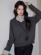 Woman standing with her hand on her head, wearing a grey v-neck sweater over a checkered collared shirt, dark wash wide leg jeans, and a black crossbody pouch.