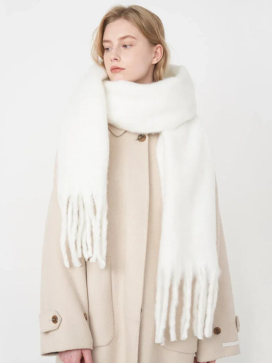 Woman wearing a white fluffy scarf draped over a beige coat, side profile