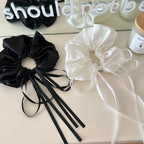 black and white satin scrunchies with long ribbon ties on a white surface
