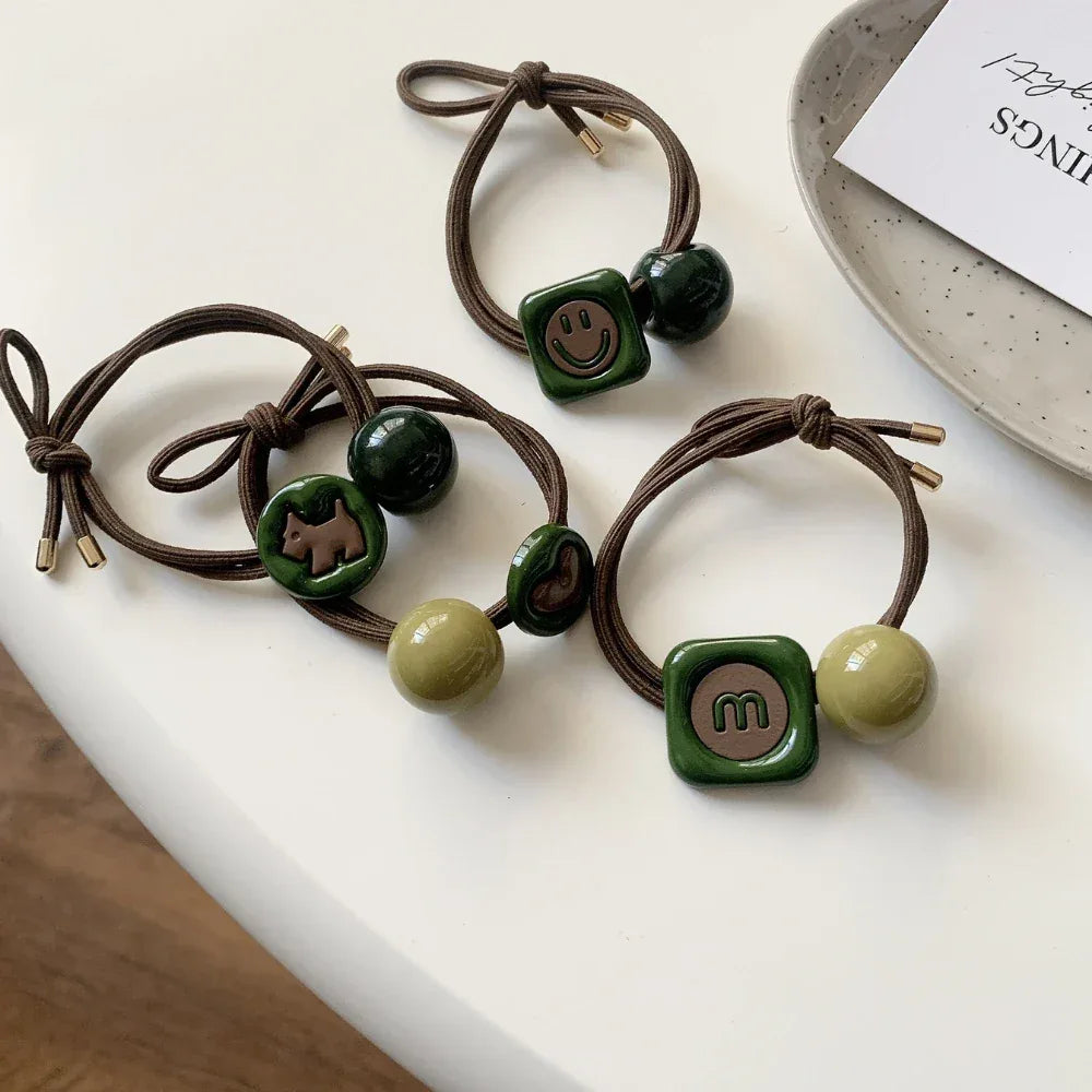 A collection of hair ties with various charms including a dog, smiley face, and letter 'm'.