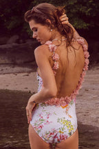 Woman in a floral print one-piece swimsuit with ruffled straps, showing the back.
