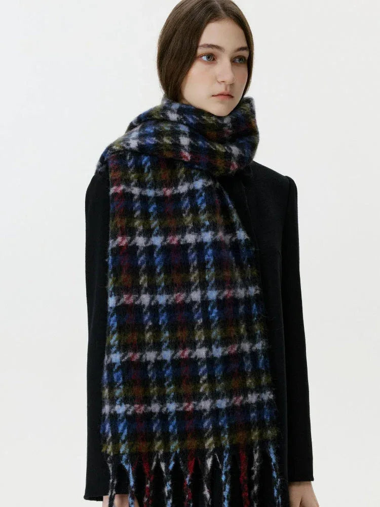 Woman wearing a black coat and a dark plaid scarf with fringe
