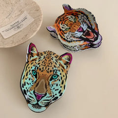 Overhead view of a leopard head accessory and a tiger head accessory on a decorative plate