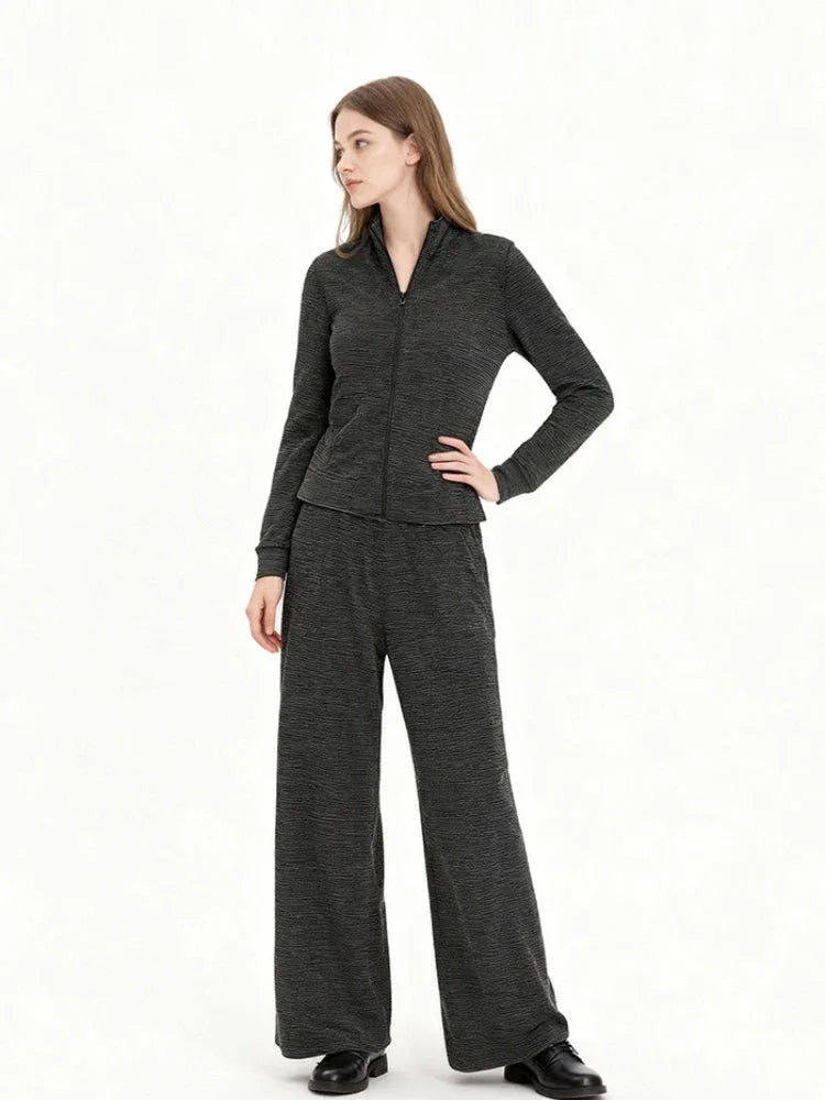 Model wearing a charcoal grey knit zip-up jacket and matching wide-leg pants, side view with hand on hip.
