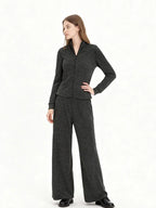 Model wearing a charcoal grey knit zip-up jacket and matching wide-leg pants, side view with hand on hip.