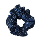 A single navy blue and white polka dot scrunchie