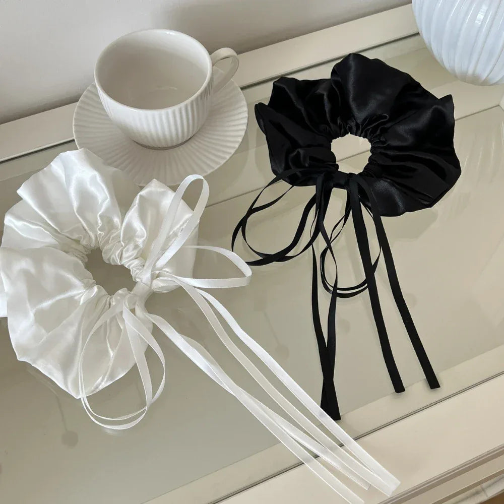 black and white satin scrunchies with long ribbon ties next to a teacup